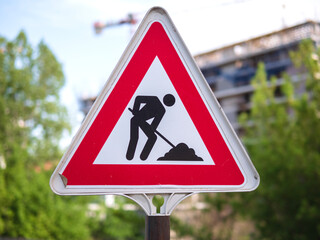 A construction sign with a triangle design. Road works sign. Red triangle sign with silhouette working person inside