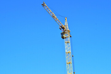 Construction. High-rise tower crane against blue sky
