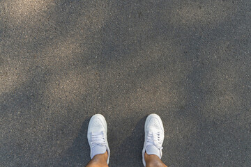 Fitness and healthy lifestyle concept. Man looking running sneakers on a asphalt road. Top view and...