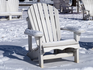 Naklejka premium A white Adirondak chairs at a waterfront park covered in snow in winter