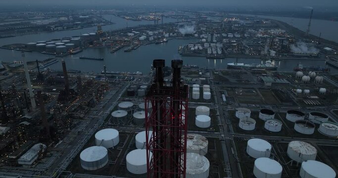 Smoke stack at a refinery in the port of Antwerp, Belgium. Industrial site. Processing of petroleum products and fossil fuels. Drone view at night. Port of Antwerp.