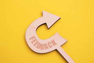 A wooden arrow symbol pointing towards the word feedback on a stylish yellow background. The font,...
