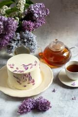 Beautiful spring cake on the background of a bouquet with lilacs. 
