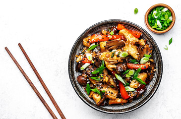 Hot stir fry chicken  slices with red paprika, mushrooms, chives and sesame seeds with ginger, garlic and soy sauce. White table background, top view