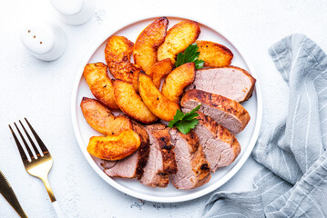 Baked pork tenderloin with caramelized apples on plate, white table background, top view - 791860849