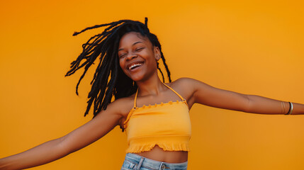 An African woman with open arms and a blissful smile, dressed in a yellow top and denim. She stands against a bright yellow background, embodying a spirit of happiness and liberation.