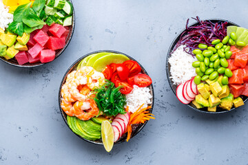 Poke bowl for balanced nutrition. Set with  tuna, salmon, shrimp avocado, mango, radish, white rice and other ingredients. Gray table background, top view
