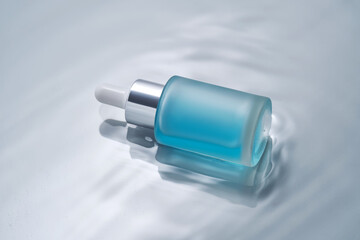 Bottles of cosmetics with a dropper in water on a blue background.