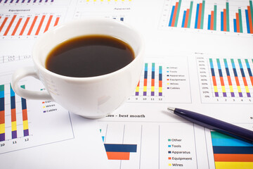Cup of coffee, ballpen and financial chart showing different production or sales statistics....