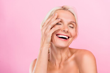 Photo of happy lovely cute retired woman applying nourishing lotion for skin health isolated on pink color background - 791873272