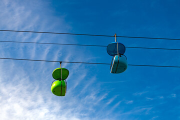 Colorful, old-fashioned cable car or chairlift in an amusement park. Green and blue empty vintage gondola against a blue sky on a sunny day in the famous boardwalk of Santa Cruz, California (USA).