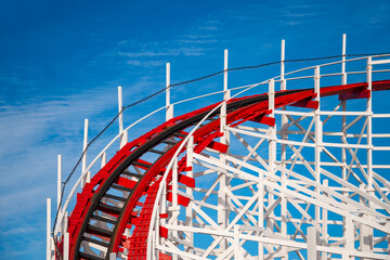Wooden roller coaster curve at a funfair. Contrasting colorful red and white painted historic track...