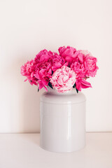 Beautiful bouquet of fresh colorful peony flowers in full bloom in vase against white background.