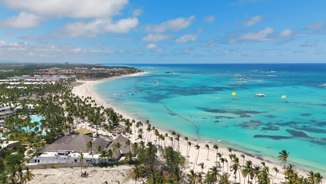 Aerial view of large white sand beach with many all inclusive hotels and resorts. Watersports excursions in turquoise Caribbean sea. Top places for summer vacations for family in Punta Cana