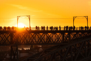 people crossing a bridge at sunset