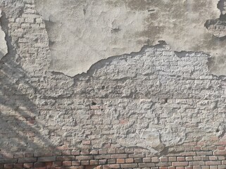 The texture of an old cracked plastered wall. Gray old wall. Rough texture