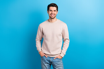 Portrait of funny satisfied man with brunet hairstyle dressed beige sweatshirt standing arms in...
