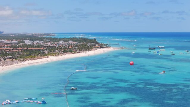 Aerial view of large white sand beach with many all inclusive hotels and resorts. Watersports excursions in turquoise Caribbean sea. Top places for summer vacations for family in Punta Cana