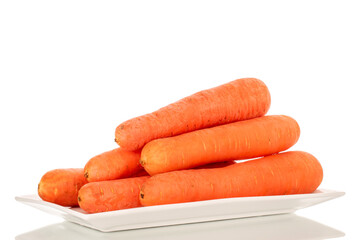 A few sweet carrots on a white ceramic plate, macro, isolated on a white background.