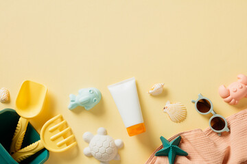 Flat lay composition with sunscreen cream in tube, children's beach toys, sunglasses, seashells, towel on sand color background.
