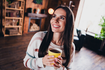 Photo of lovely young woman hold coffee mug drinking look empty space wear striped outfit interior home living room in brown warm color