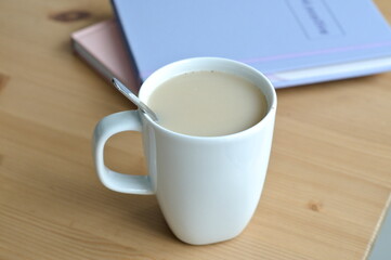 cup of coffee with milk and notepads on wood table