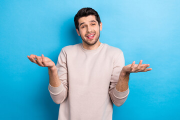 Photo of young man shrug shoulders dont know wear beige sweatshirt isolated on blue color background