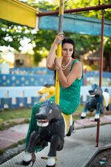 girl sitting on a carousel, carousel horses, abandoned park, children's entertainment, carousel for kids, childhood in Cuba, woman in evening dress, woman sitting on a horse