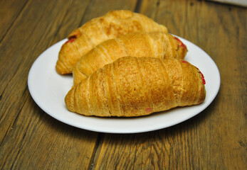 croissant on a plate. fresh delicious croissants on a white plate on a wooden table