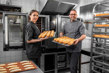 Man and woman working in a bakery and looking contented