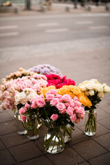 Bouquets of soft roses in a glasses decanters which stands on a street - 791933627