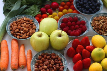 Apples, lemons, bananas, berries, carrots, leek, tomatoes, radishes, spinach and various nuts on...