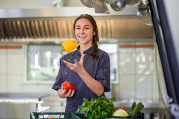 Young smiling woman with peppers in hands in the kitchen