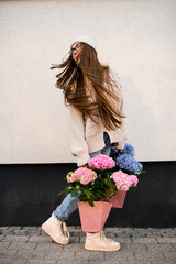 Turned around girl in a hat and jeans with pink and blue bouquets in the hands - 791938617