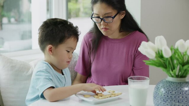 Mother and son practicing counting with cookies at the kitchen table in a home