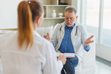 Senior man doctor examining young woman in doctor office or at home. Girl patient and doctor have...
