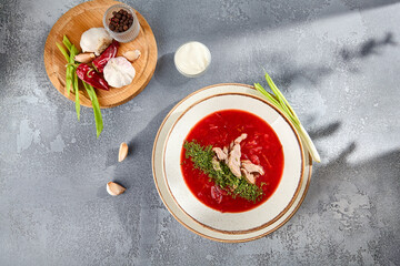 Traditional borscht with beef strips and sour cream garnish, vibrant red beet soup on speckled...