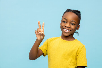 Smiling cheerful African American little boy showing v-sign