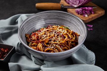 Side view, horizontal shot of a delicious udon dish stir-fried with chicken and vegetables in a...