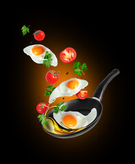 Three fried eggs with tomatoes and parsley fly out of the pan on a black background