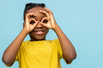 Joyful African American little boy making binoculars with hands - 791950084