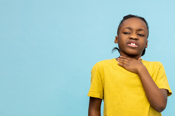 Unhealthy dark- skinned little boy holding painful neck