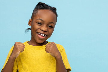 Overjoyed dark- skinned little boy showing clenched fists