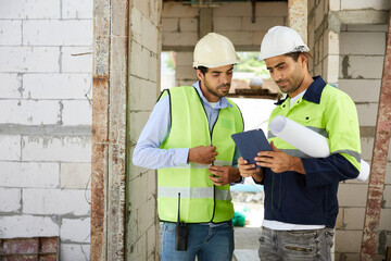 workers or architects meeting and working on tablet at construction site