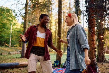 Carefree couple having fun while dancing during their camping in nature.