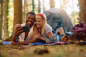 Happy couple taking selfie while camping in the woods.