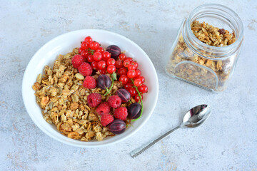 a bowl of granola with berries and a spoon and a bowl of cereal  