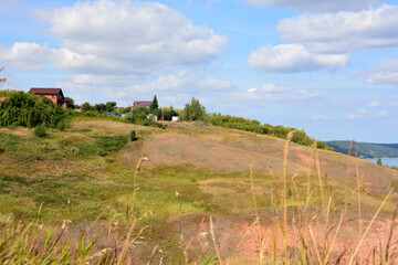 a hill with a house on the top of it and blue sky with clouds  
