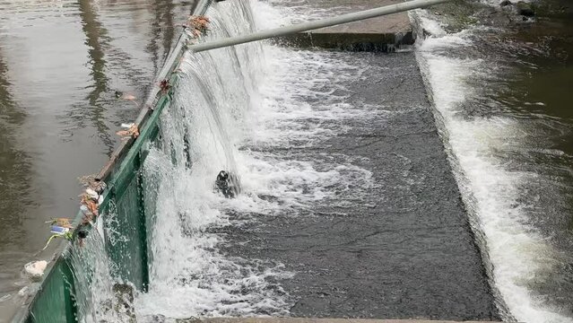 A river with a green wall plastic artificial dam and water flowing