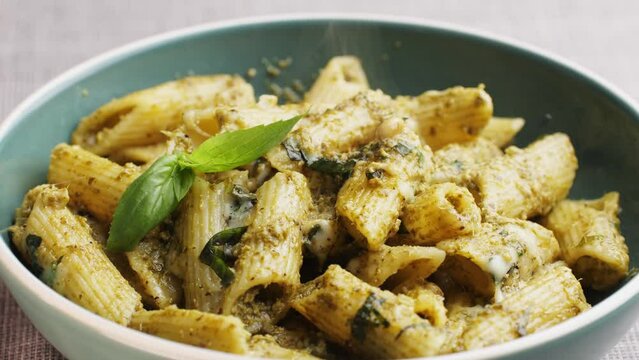 Traditional Italian pesto pasta, chef cooking penne with green basil sauce in pan, close up of Italian cuisine, vegan food.